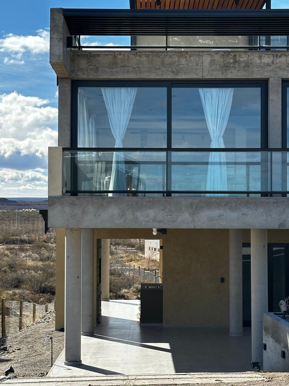 Vista desde abajo: los pilotes, el nivel principal vidriado y la terraza, fotografía de obra
