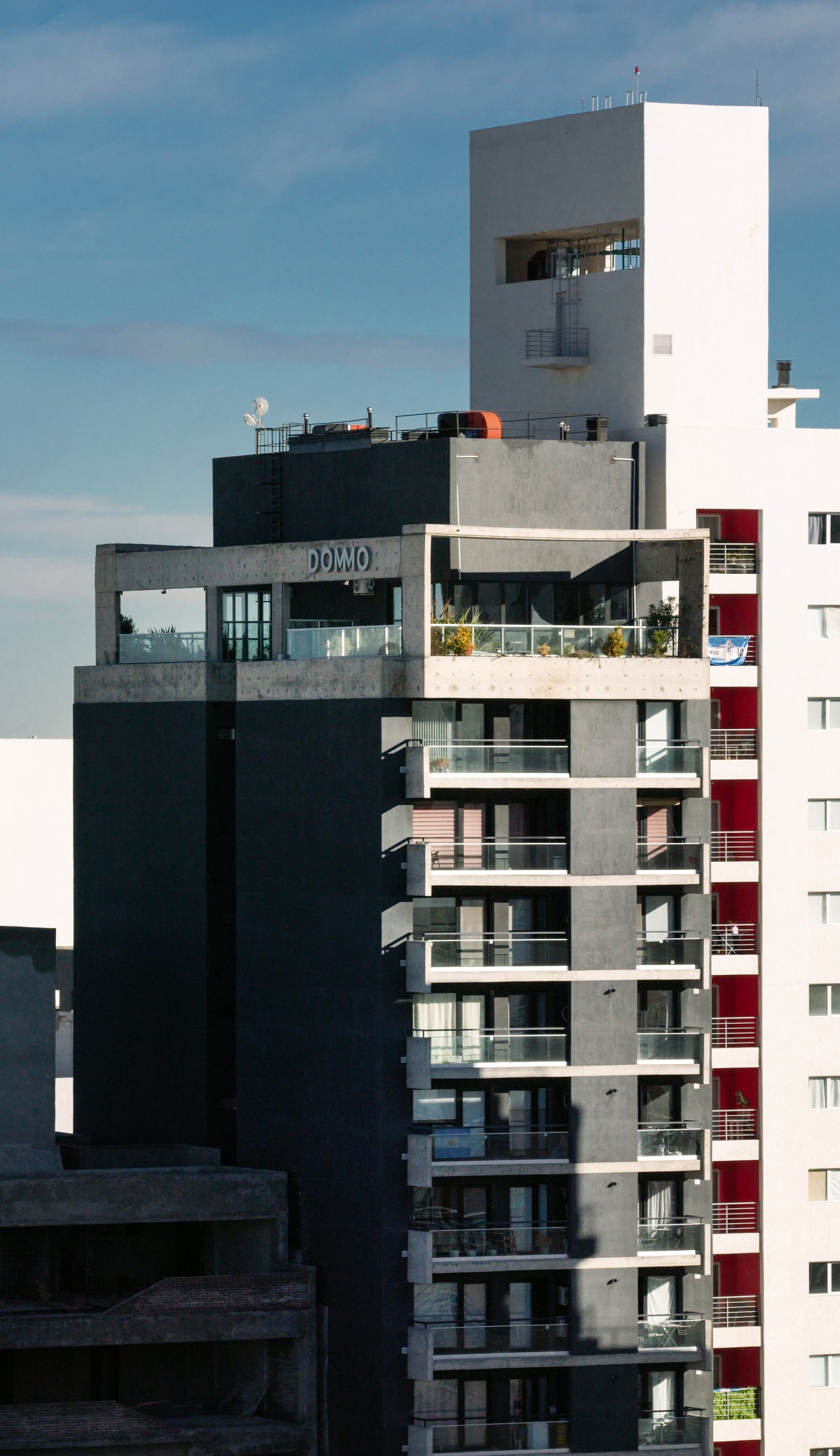 Coronamiento con el nombre del edificio y los balcones de hormigón, fotografía de obra